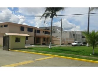Two-story beige residence with secure access booth and palm trees Colon Panama